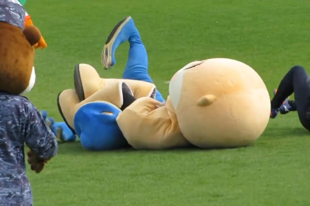 A mascot gets arm-barred by his opponent during an exhibition soccer match.