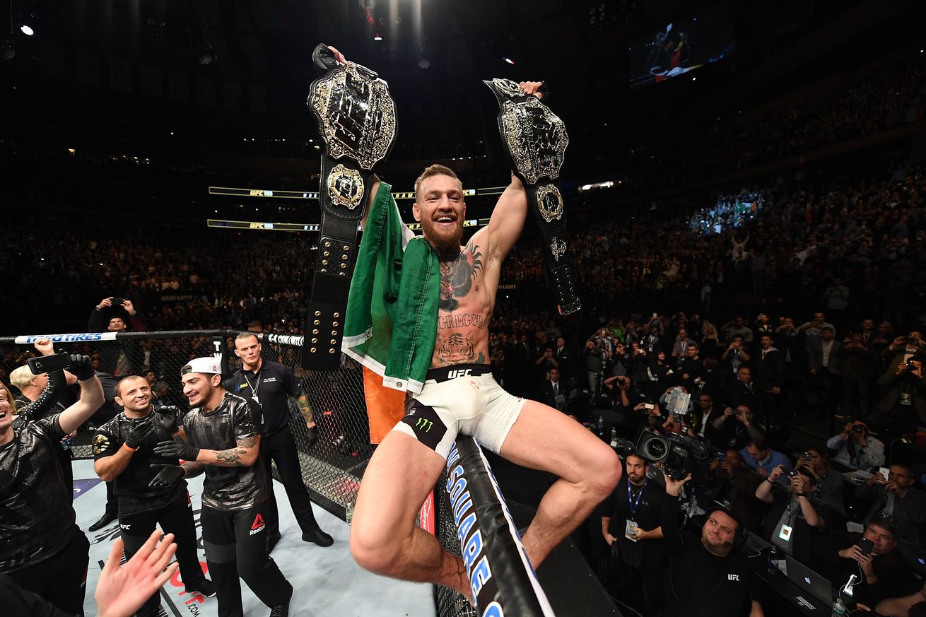Conor McGregor holds his two UFC belts aloft after beating Eddie Alvarez at UFC 205.